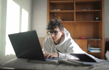 Ein Junge mit Brille sitzt vor einem Laptop.
