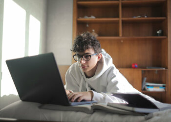 Ein Junge mit Brille sitzt vor einem Laptop.