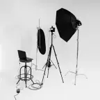 Ein Kamera-Setting mit Stuhl, Belichtung und der Kamera. aus der verschiedene Kabel ragen. Der Hintergrund ist blank.