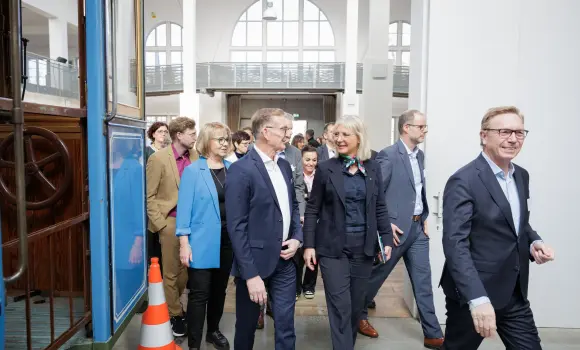 Frau Staatsministerin geht mit den restlichen Besuchern, an einer ausgestellten Tram vorbei, in den vorderen Bereich des Museums.