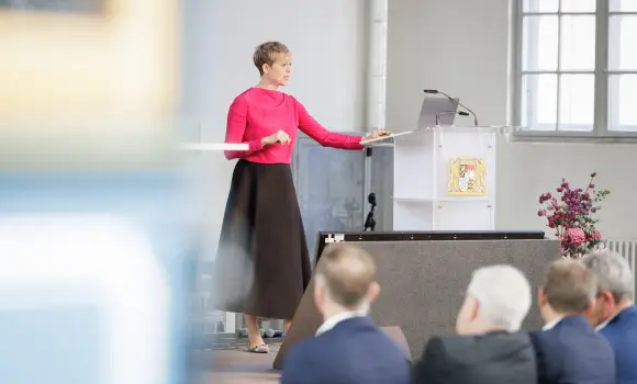 Keynote-Speakerin Steffi Burkhart tippt am Laptop und präsentiert das Thema. Die Zuhörer blicken in ihre Richtung und hören aufmerksam zu.