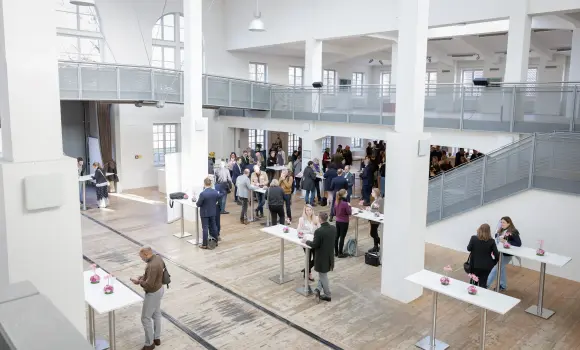 Vogelperspektive mit den ersten Besuchern, die an Stehtischen Platz nehmen und in das MVG-Museum strömen.