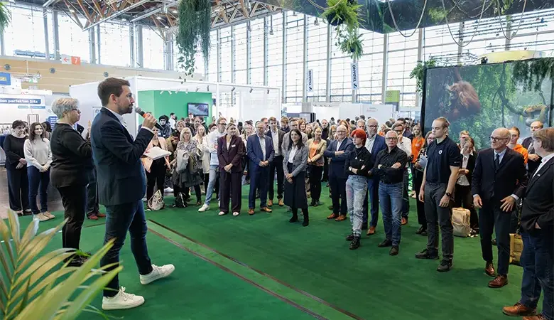 Ein Moderator spricht auf einer Bühne zu Publikum